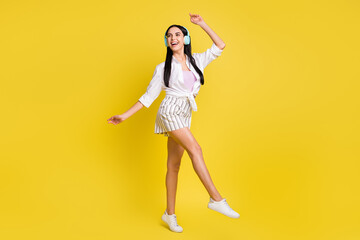 Fototapeta na wymiar Full size photo of young pretty smiling cheerful positive girl dancing in headphones isolated on yellow color background