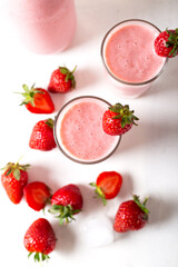 Fresh homemade cold strawberry smoothie with ice cubes and fresh strawberries on white background. Top view. 
