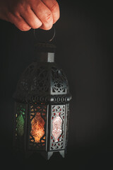 A man holds a glowing arabic lantern on a dark background. Muslim holiday of the holy month of Ramadan Kareem