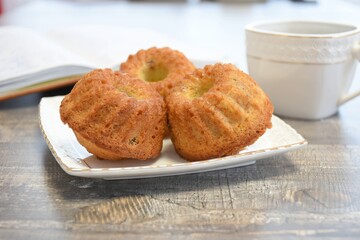 Cupcakes with raisins on a white plate with a white cup on a blurred background in warm colors