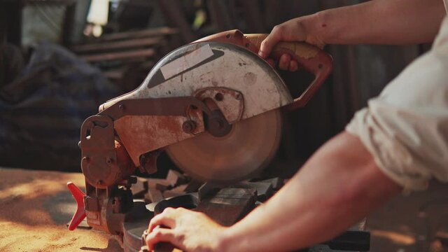 A carpenter cutting wooden plank with electric buzzsaw. Woodworking and carpentry. Craftsmanship.	
