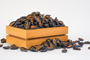 Natural dried fruits in wooden box. Dried plums on white background. Health, organic concept.