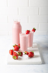 Fresh homemade cold strawberry smoothie with ice cubes and fresh strawberries on white background.