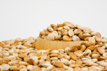 Nuts in a wooden bowl on white background. Apricot kernels heap on white. Free space for text. Products show for sale. Fresh roasted pistachio nuts. Copy space. Studio shot.