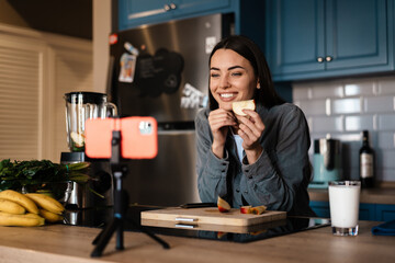 Smiling woman taking selfie footage with apple on cellphone