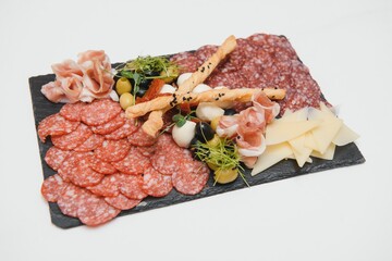 Appetizers with differents antipasti, charcuterie, snacks and red wine on white background. Sausage, ham, tapas, olives and crackers for buffet party. Top view, flat lay