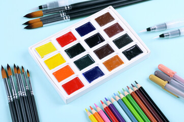 Colorful gouache paints and brushes on the blue background.