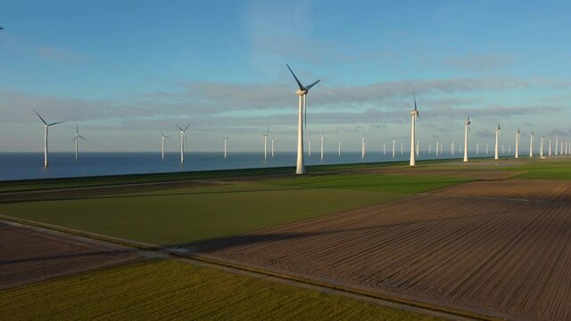 Wind turbines on a levee and off the coast of Flevoland on the IJsselmeer coast in The Netherlands aerial view