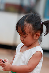 Fototapeta premium Portrait of asian baby girl, a cute face,With holding fruit in hand.