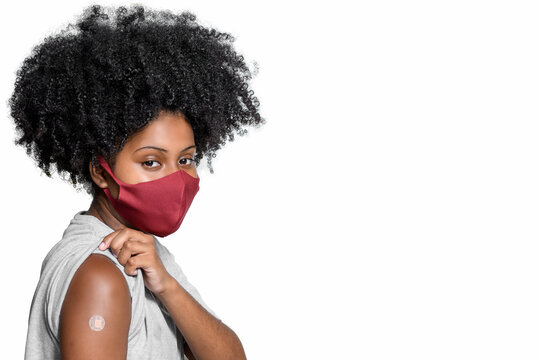 Black Teenager Wearing Protective Mask Against Covid-19 With A Smile On His Face Shows The Vaccine Brand, Isolated On White Background