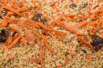 Ready dish - pilaf close-up for the backdrop. Carrots, rice, meat, spices. The concept of an oriental traditional hearty dish.