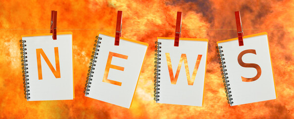 image of notebooks with cut letters NEWS hanging on a rope against a background of raging flames