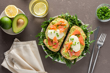 Delicious hearty breakfast, sandwiches with avocado paste, salmon and mozzarella on a plate with arugula and pea sprouts