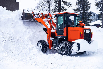 Snow removal excavator tractor cleaning on winter road covered with snow