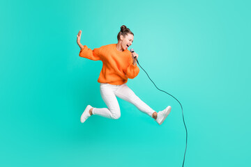 Full size profile side photo of young crazy screaming girl jumping singing in microphone isolated...