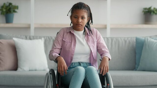 Serious Disabled African Teen Girl Sitting In Wheelchair At Home
