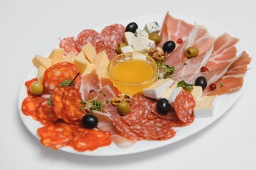 Appetizers with differents antipasti, charcuterie, snacks and red wine on white background. Sausage, ham, tapas, olives and crackers for buffet party. Top view, flat lay