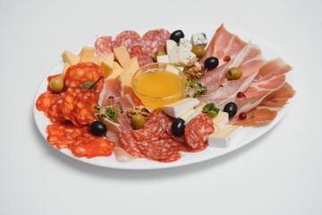 Appetizers with differents antipasti, charcuterie, snacks and red wine on white background. Sausage, ham, tapas, olives and crackers for buffet party. Top view, flat lay