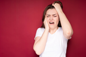 Brunette with long hair suffers from headache due to the installation of braces grabbing her hair with her hands