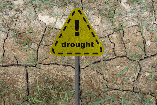 yellow drought hazard sign on cracked dry ground background