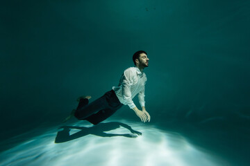 Muslim man swimming underwater in pool