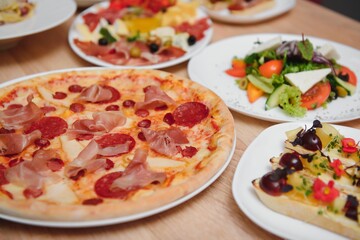 Different salads on wooden table, top view. Vegetable salad, Salad with smoked duck, Grilled chicken Caesar salad.