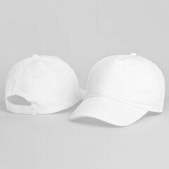 Two white baseball caps isolated on a gray background front and back view, cap mock up and template