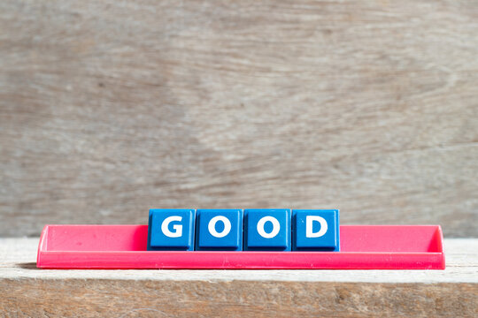 Tile letter on red rack in word good on wood background