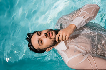 Top view of bearded arabian businessman in shirt swimming in pool