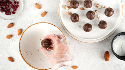 Step by step cooking Energy balls. Step 10 recipe of no bake energy balls. Making round balls from the mixture of nuts, dates, cocoa powder, coconut flakes, oats and dried cranberry. Healthy eating.