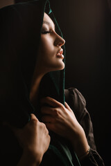 fashion portrait of woman in green scarf or hidjab posing on dark background