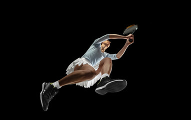 Female professional tennis player in action, motion isolated on black background, look from the...