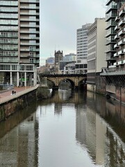 A river running through Manchester City centre with modern architecture and landmark buildings. 