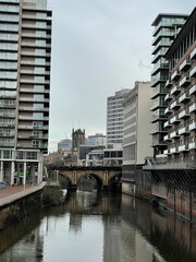 A river running through Manchester City centre with modern architecture and landmark buildings. 