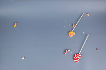 Broken in pieces candy on a stick. Smashed lollipop on grey background, top view with copy space.