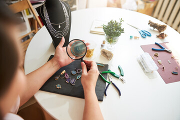 Craftswoman inspecting a gemstone through a magnifying glass