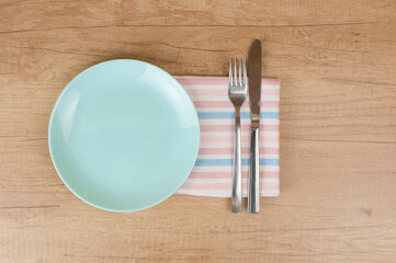 Empty plate, knife, fork and towel over wooden table background. View from top with copy space.