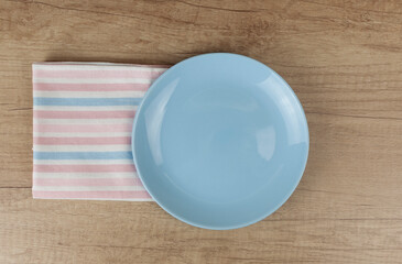 Empty plate and towel over wooden table background. View from above with copy space