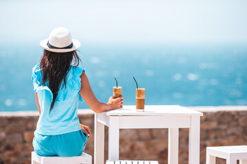 Young woman drinking cold coffee enjoying sea view