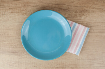 Empty plate and towel over wooden table background. View from above with copy space