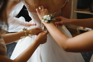 Bridal morning, bride wears dress. Groom helping fiancee to get dressed, adjusting buttons on wedding gown, rear view. close-up, crop