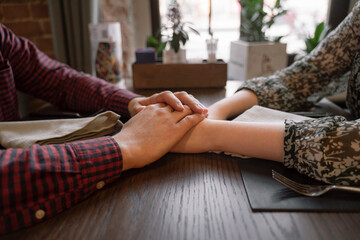 Obraz premium young couple on the first date holding hands, close-up hands