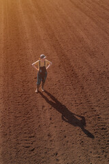 Female farmer looking over ploughed field, drone photography