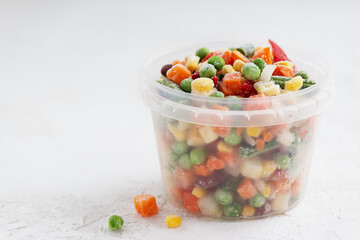 Mix of frozen vegetables in a container.