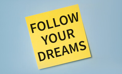 FOLLOW YOUR DREAMS text on sticker against blue background. Minimalism
