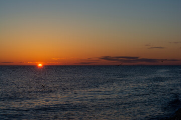 colorful sunset with a cloudless sky overlooking the sea and the setting bright sun