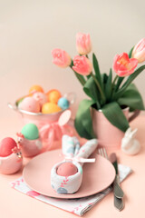 Festive Easter table setting with napkin Easter Bunny on pink table. Easter celebration concept. Soft focus. Copy space