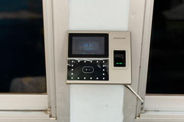 The fingerprint scanner with clock on the wall. Equipment for working time in office.