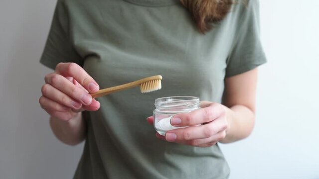 Woman holds bamboo toothbrush and soda powder in her hands