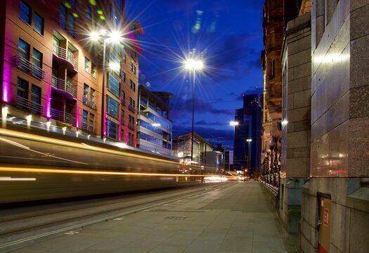 City street at night with a moving tram creating light trials. Long exposure night image.  Taken in Manchester England. 